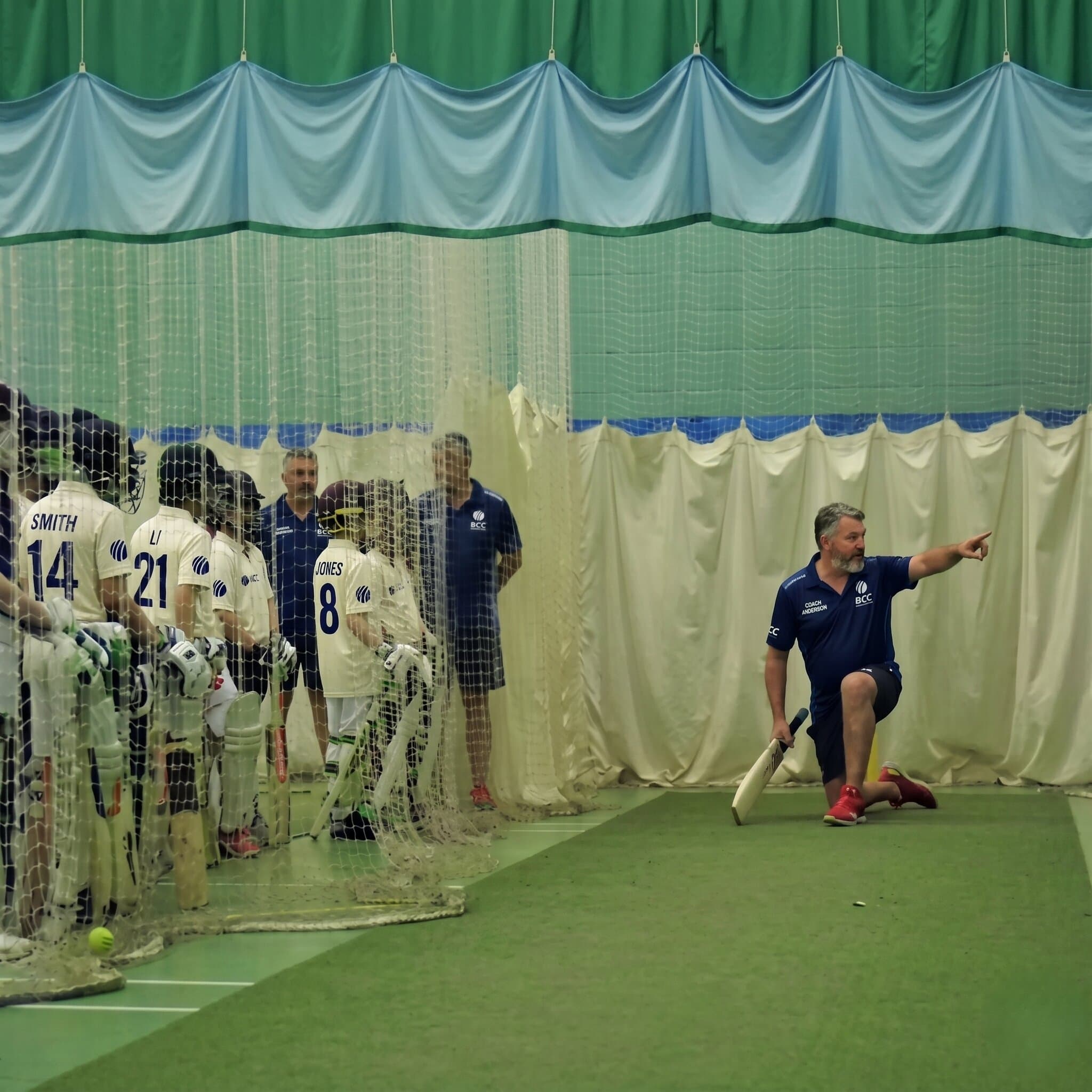 BCC coach providing one-on-one bowling technique advice to a player